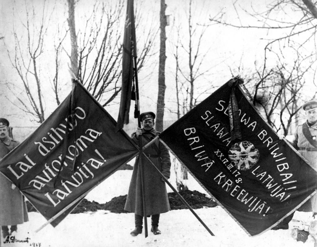 Vidzemes latviešu strēlnieku pulka 3. rotas strēlnieki ar karogiem Februāra demokrātiskās revolūcijas upuru piemiņas demonstrācijā Rīgā. 1917. gada 10. marts